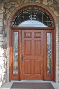 Entry door with side panes and large arched transent window above